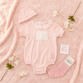 Pink baby romper set on soft pink background with flowers